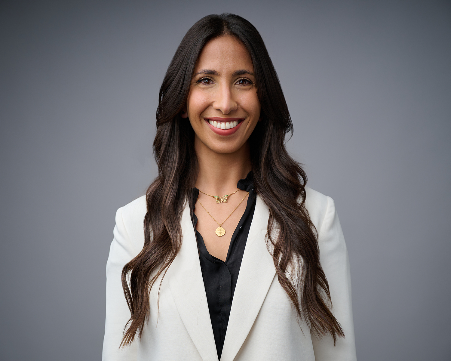 Professional woman in a white blazer against a gray studio background