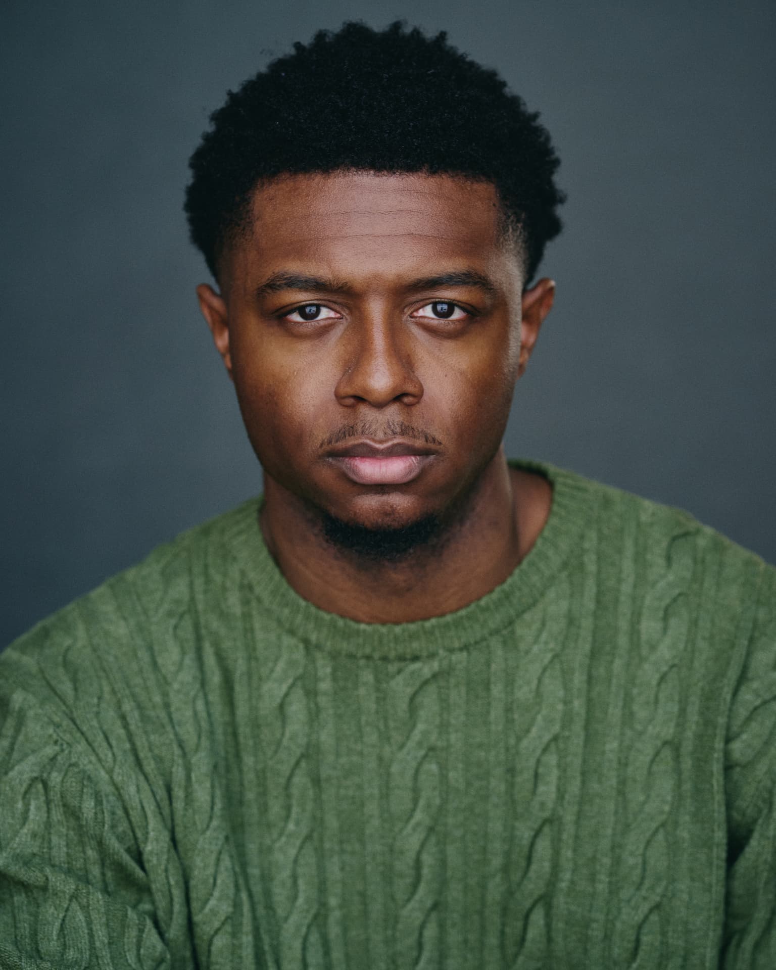 Professional man in a green sweater against a gray studio background